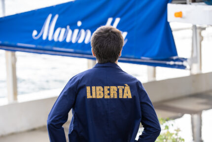 Personne portant le bleu de Chine Libertà or brodé, visuel doré manuscrit dans le dos, coupe droite et style engagé