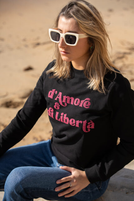 Femme portant de face le sweat noir Amore è Libertà rose paillettes, coupe moderne, décontratée et confortable