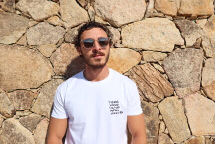 Homme portant le T-shirt blanc brodé niveau la poche gauche en noir : Terra, lingua, cultura, popolu, nazione
