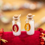 Ensemble de fioles de sel en verre avec médaille miraculeuse, bouchon en liège et sel purificateur, symboles de protection et de spiritualité.