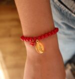 Personne portant le bracelet de perle de verre rouge avec 2 pampilles : médaille miraculeuse orange et morceau de corail