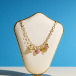 Collier doré avec pampilles ex-voto, cauri, cœur rose en verre et soleil – Plaqué or, exclusivité L’Oru