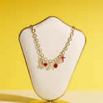Collier doré avec pampilles symboliques (poing, cœur, croix, médaille miraculeuse) et pierres rouges – Plaqué or, exclusivité L’Oru