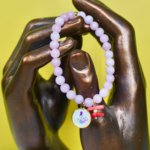 Bracelet Madonuccia rose à 2 pampilles en perles de verre roses, orné d’une médaille représentant la Madonuccia et d’un fragment de corail naturel, symboles forts de la culture corse et méditerranéenne.