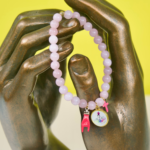 Bracelet Madonuccia rose à 3 pampilles en perles de verre roses, orné d’une médaille représentant la Madonuccia, d’une petite croix rose et d’une corne rose, symboles corses de protection et de spiritualité.