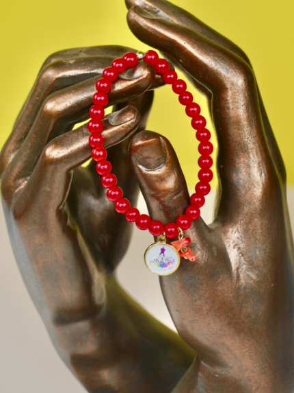 Bracelet Madonuccia rouge à 2 pampilles en perles de verre rouges, orné d’un fragment de corail naturel et d’une médaille représentant la Madonuccia, symbole de la tradition corse et de la culture méditerranéenne.