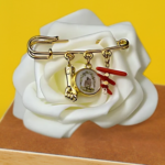 Broche artisanale San Ghjisè avec 3 pampilles : médaille du saint, bras en acier inoxydable et corail naturel. Bijou protecteur de L’Oru.