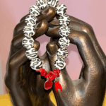 Bracelet en perles silicone motif léopard avec fragments de corail rouge, médaille miraculeuse rouge et corne protectrice, inspiré des traditions corses.