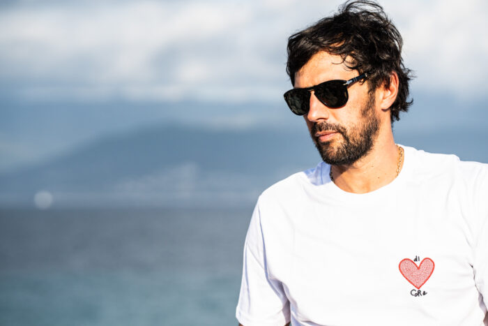Homme portant le t-shirt brodé blanc Di Core, cœur rouge brodé visible côté cœur, coupe droite et look sobre
