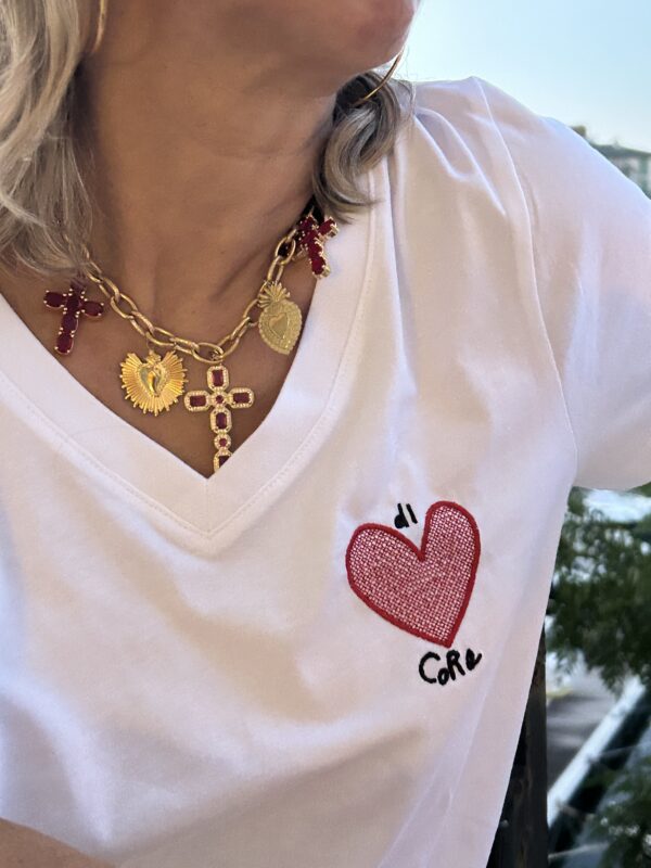 Femme portant le tee-shirt brodé Di Core en blanc col V, visuel cœur brodé visible sur la poitrine, silhouette féminine élégante