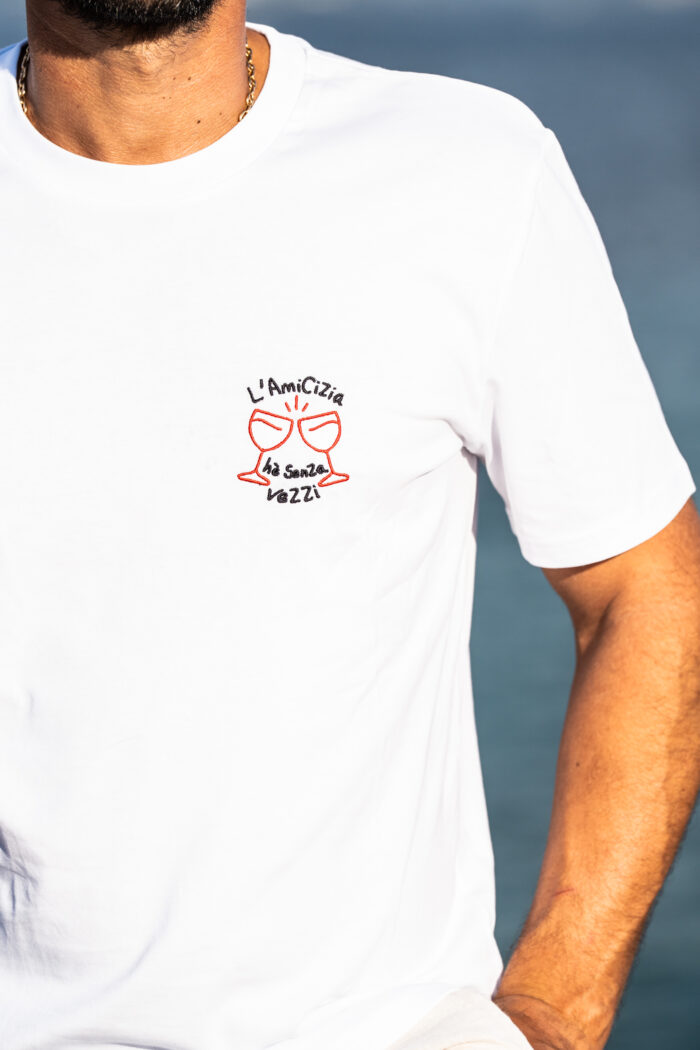 Détail broderie du tee-shirt Amicizia blanc pour homme, deux verres brodés rouges avec message L’amicizia hè senza vezzi