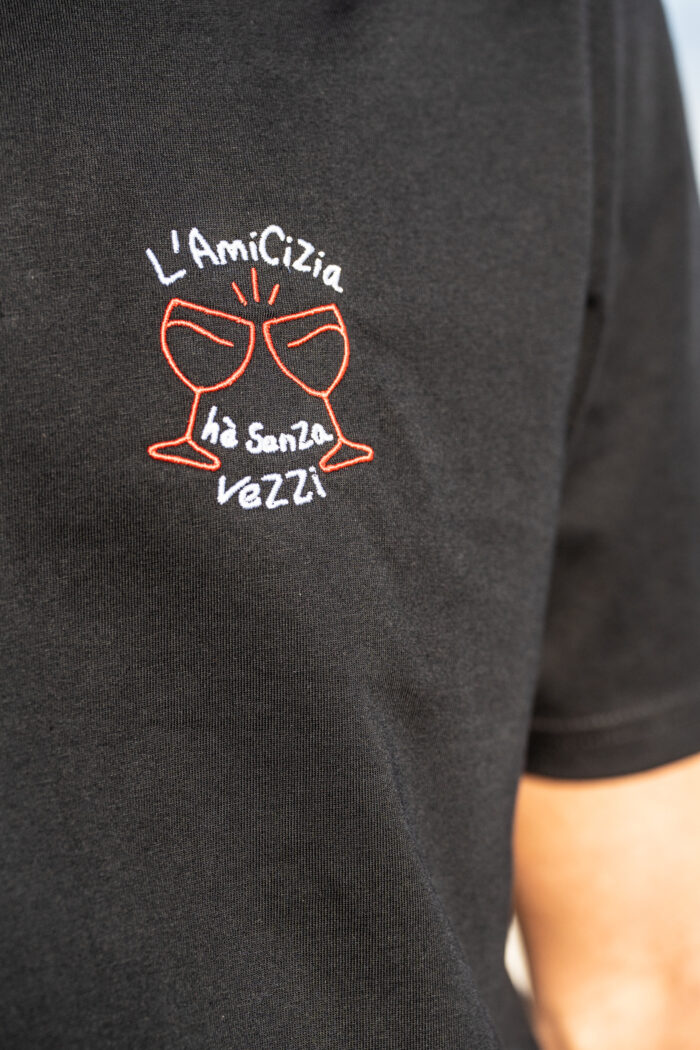 Détail broderie du tee-shirt Amicizia noir pour homme, deux verres brodés rouges avec message L’amicizia hè senza vezzi