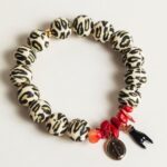 Bracelet en perles silicone motif léopard avec fragments de corail rouge, médaille miraculeuse noire et corne protectrice, inspiré des traditions corses.