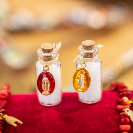 Ensemble de fioles de sel en verre avec médaille miraculeuse, bouchon en liège et sel purificateur, symboles de protection et de spiritualité.
