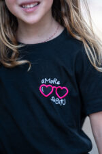 Enfant portant le tee-shirt brodé Amore Subitu noir, message humoristique avec lunettes en forme de cœur, coupe unisexe, t-shirt blanc en coton