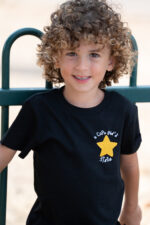 Enfant portant un tee-shirt brodé noir Capu ind’e stelle avec étoile jaune sur la poitrine, coupe unisexe et tissu 100 % coton, coloris noir