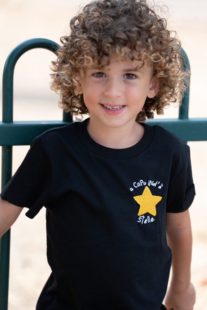 Enfant portant un tee-shirt brodé noir Capu ind’e stelle avec étoile jaune sur la poitrine, coupe unisexe et tissu 100 % coton, coloris noir
