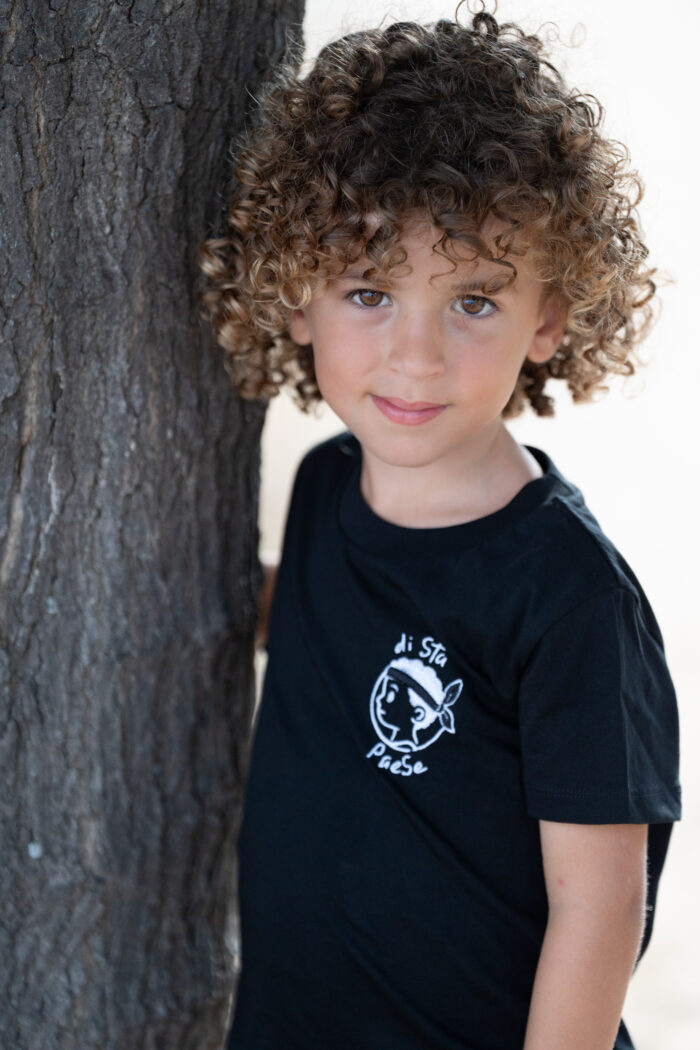 Garçon portant le T-shirt noir brodé Di stu paese, motif personnage corse avec bandera, coton doux et coupe unisexe