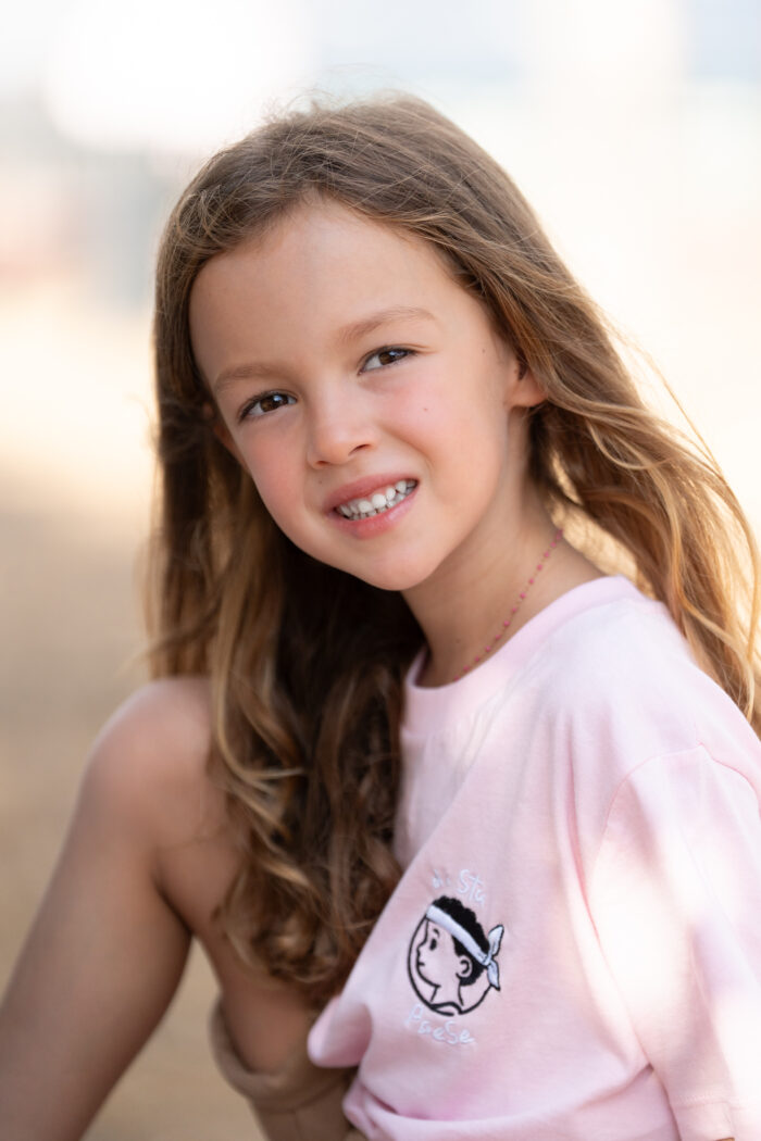 Fille portant le T-shirt rose brodé Di stu paese, motif personnage corse avec bandera, coton doux et coupe unisexe