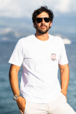 Homme portant le tee-shirt brodé Amicizia blanc de buste, message brodé visible sur le cœur, style simple et convivial