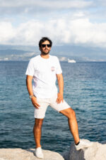 Homme portant le tee-shirt brodé Amicizia blanc en pied, message brodé visible sur le cœur, style simple et convivial