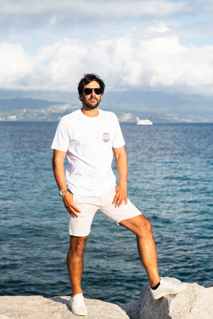 Homme portant le tee-shirt brodé Amicizia blanc en pied, message brodé visible sur le cœur, style simple et convivial